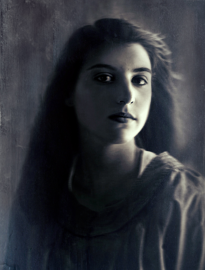 Moody soft-focus head and shoulders black and white portrait of a pretty teenage girl with large brown eyes and long dark hair.