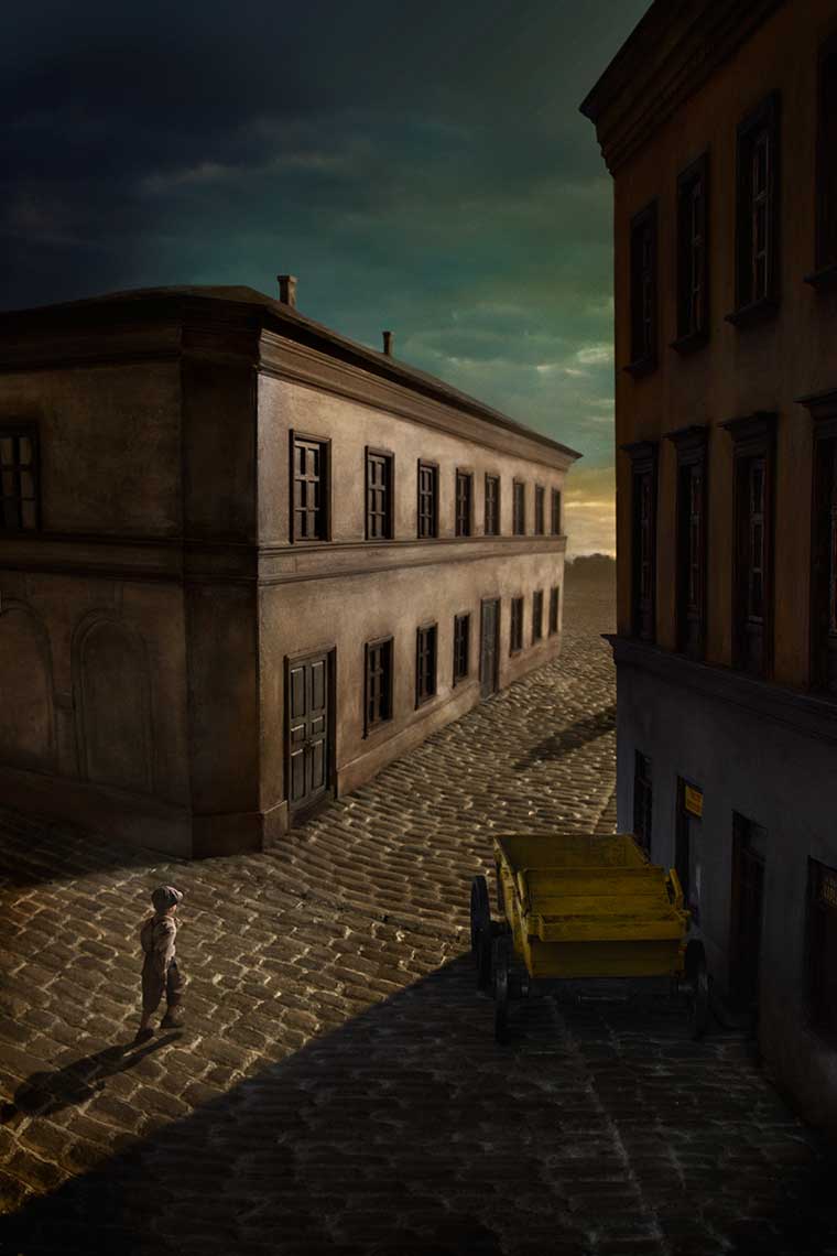 An homage to Giorgio de Chirico’s painting, “Mystery and Melancholy of a Street”, bird’s-eye-view of a young boy running down a surreal, lonely 1930s’ Eastern European cobblestone street  towards a mysterious figure’s shadow.
