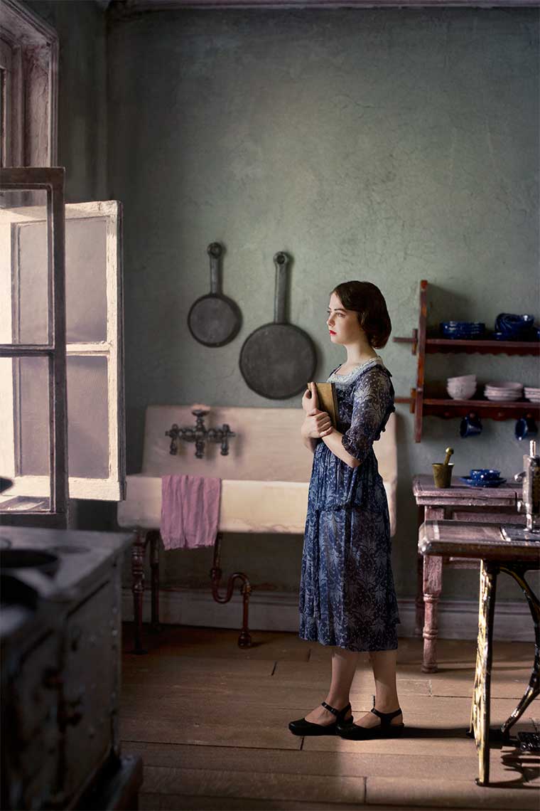 Painterly photomontage of a beautiful young woman with 1930s’ hairstyle and dress, stands in Vermeer-like soft window light in 1930s’ kitchen gazing out the window.