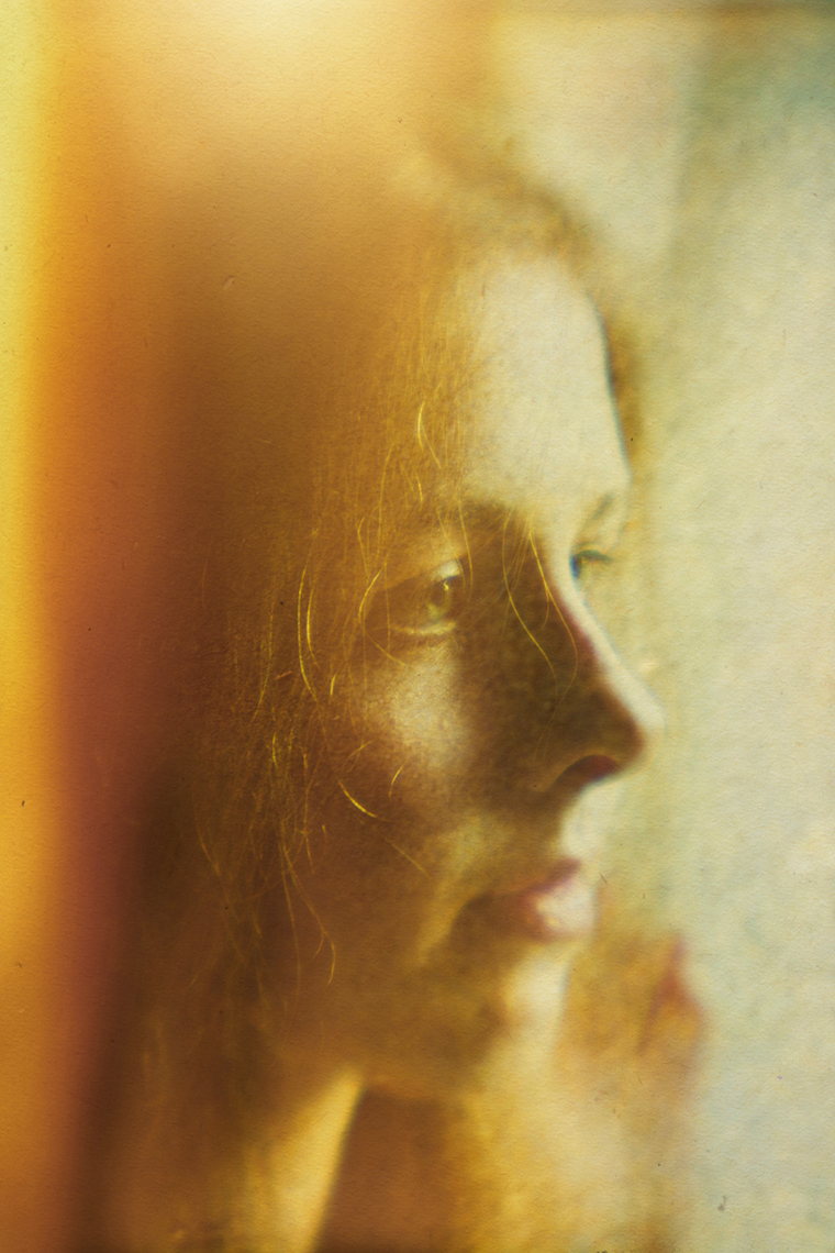 Golden-colored soft focus closeup portrait of a pretty teenage girl gazing off camera.